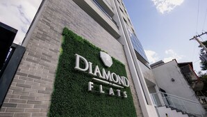 Un edificio con un cartel que dice 'DIAMOND FLATS' y una escalera que lleva a la entrada.