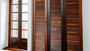 A bedroom with a bed, wooden wardrobe, and a window. - Spacious Colonial House with Pool and Incredible View (São Lourenço)