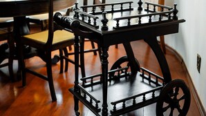 A dining area with a wooden table, chairs, and a decorative cart. - Spacious Colonial House with Pool and Incredible View (São Lourenço)