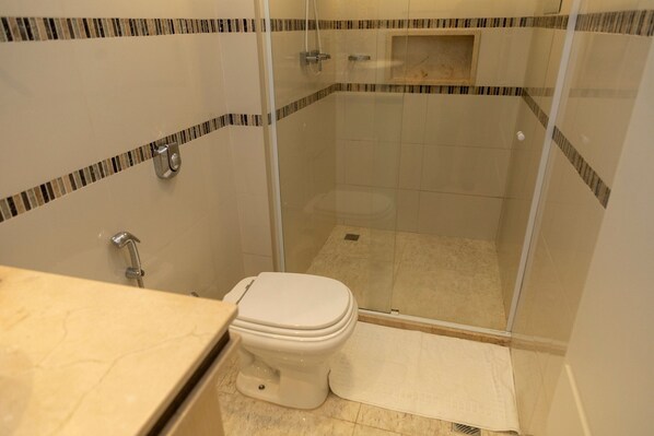 A bathroom with a toilet, shower, and a glass-enclosed shower stall.