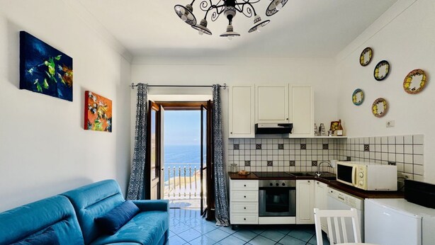 Ett kompakt bostadsutrymme med en soffa, ett litet kök och utsikt mot omgivningen.