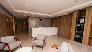 A modern hotel lobby with a reception desk, seating area, and a refrigerator stocked with beverages. - Brand New Flat in the City Center with Air Condit. (São Lourenço)