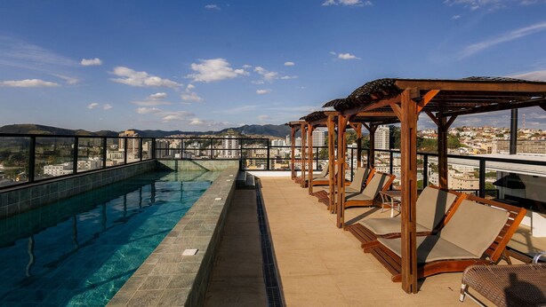 A rooftop pool with clear blue water, wooden pergolas, and lounge chairs. - Brand New Flat in the City Center with Air Condit. (São Lourenço)