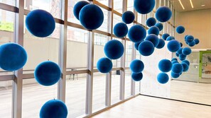 Un intérieur moderne avec de grandes fenêtres, un plancher en bois et des objets sphériques bleus suspendus au plafond.