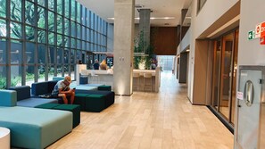 Un hall d’entrée moderne avec des espaces de détente, un comptoir d’accueil et de grandes fenêtres.