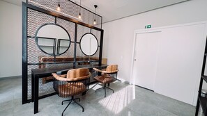A modern room with a black mesh partition, two round mirrors, a wooden table, and four leather chairs.