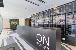 A reception desk with a logo, a wall with hanging wine glasses, and a green wall with a quote.