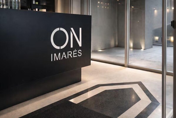 A reception desk with a logo, a modern interior with glass walls, and a geometric floor pattern.
