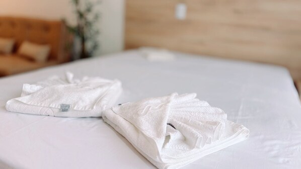A neatly made bed with folded white towels and a wooden headboard.