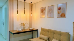 A room with a sofa, a table with a vase and glasses, and two framed artworks on the wall. - High Standard Flat - Best area of the city! (São Lourenço)
