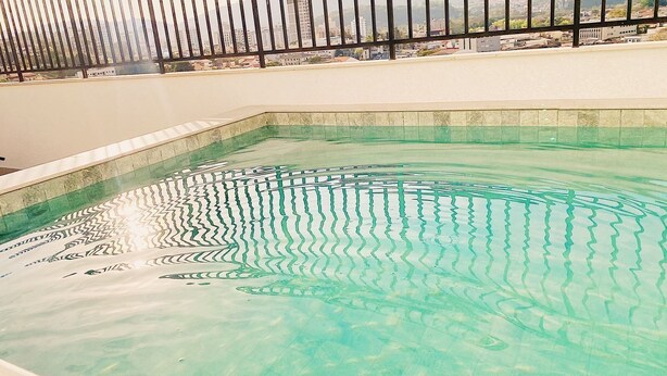 A swimming pool with clear water, surrounded by a tiled deck and a metal railing. - High Standard Flat - Best area of the city! (São Lourenço)