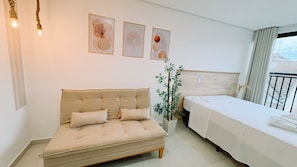 Una habitación con sofá, cama, planta en maceta y obras de arte en la pared.