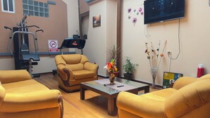 A room with a treadmill, exercise equipment, a sofa, a coffee table, and a TV mounted on the wall. - Travel House Quito (Quito)