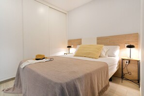 Ein ordentlich bezogenes Bett mit Kopfteil, Nachttischlampen und einem Nachttisch mit Steckdose.