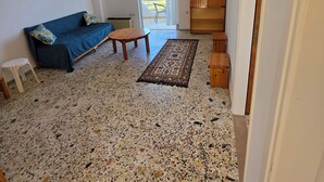 Un saló amb un sofà, una taula de centre, una catifa i un armari de fusta.