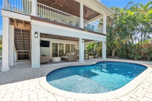 A two-story house with a swimming pool, outdoor seating, and a covered patio area. - Coastal Livin' by Duncan Real Estate (Holmes Beach)