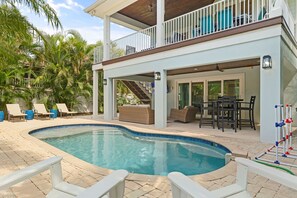 Una piscina con sillas de descanso, un patio techado y una escalera que conduce a un nivel superior.