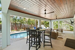 Ein überdachter Außenbereich mit Pool, Holzboden und Gartenmöbeln.