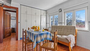 Et spiseområde med et bord dækket til to personer, en sofa og udsigt til det fri.