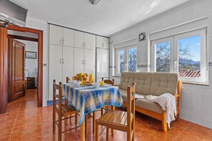 A dining area with a table set for two, a sofa, and a view of the outdoors.