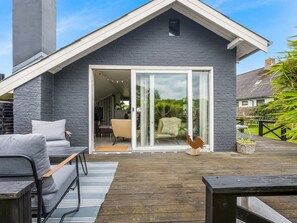 A modern house with a grey brick exterior, a wooden deck, and a sliding glass door leading to an interior space. - "Bo" - 250m from the sea by Interhome (Hadsund)
