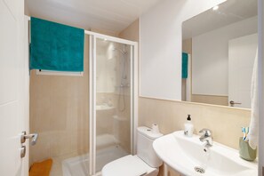Une salle de bain équipée d’une douche, de toilettes, d’un lavabo et d’un miroir.