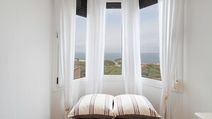 A bedroom with a view of the sea, a bed with striped pillows, and sheer curtains. - Apartment 'Sa Calma 2 - 1D' with Sea View, Wi-Fi and Air Conditioning (Begur)