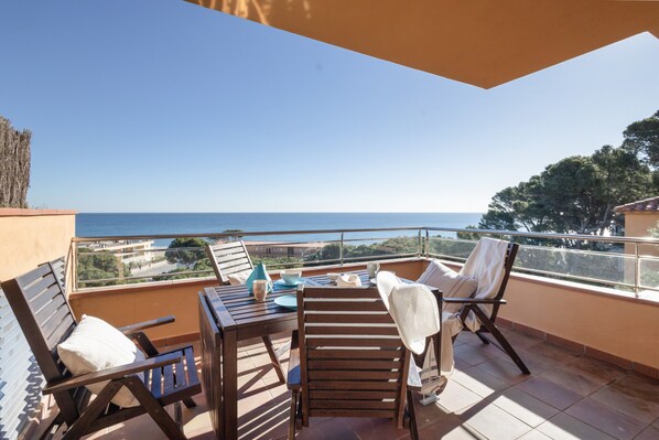 Un balcon avec une table, des chaises et une vue sur la mer.