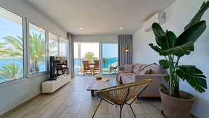 Una sala de estar moderna con ventanas amplias, un sofá, una mesa de centro y una planta en maceta.