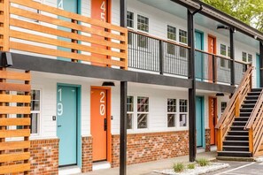 Un edificio de varios pisos con puertas numeradas, un balcón y una escalera.