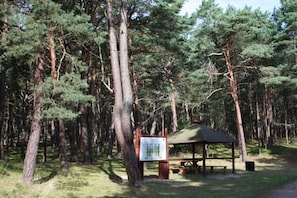 Ein bewaldetes Gebiet mit einem h ölzernen Picknickunterstand und einem Hinweisschild.