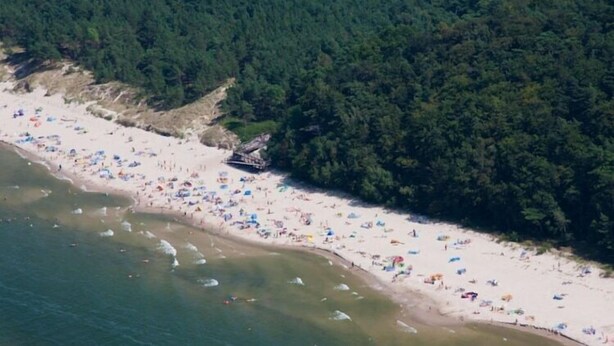A beach with numerous umbrellas and people, surrounded by dense forest. - New apartment in Wisełka (Wisełka)
