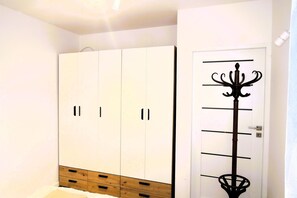 A room with a white wardrobe, a wooden cabinet, and a coat rack with a black handle. - New apartment in Wisełka (Wisełka)