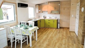 Une cuisine compacte avec un coin repas, un plancher en bois et une fenêtre donnant sur l’extérieur.