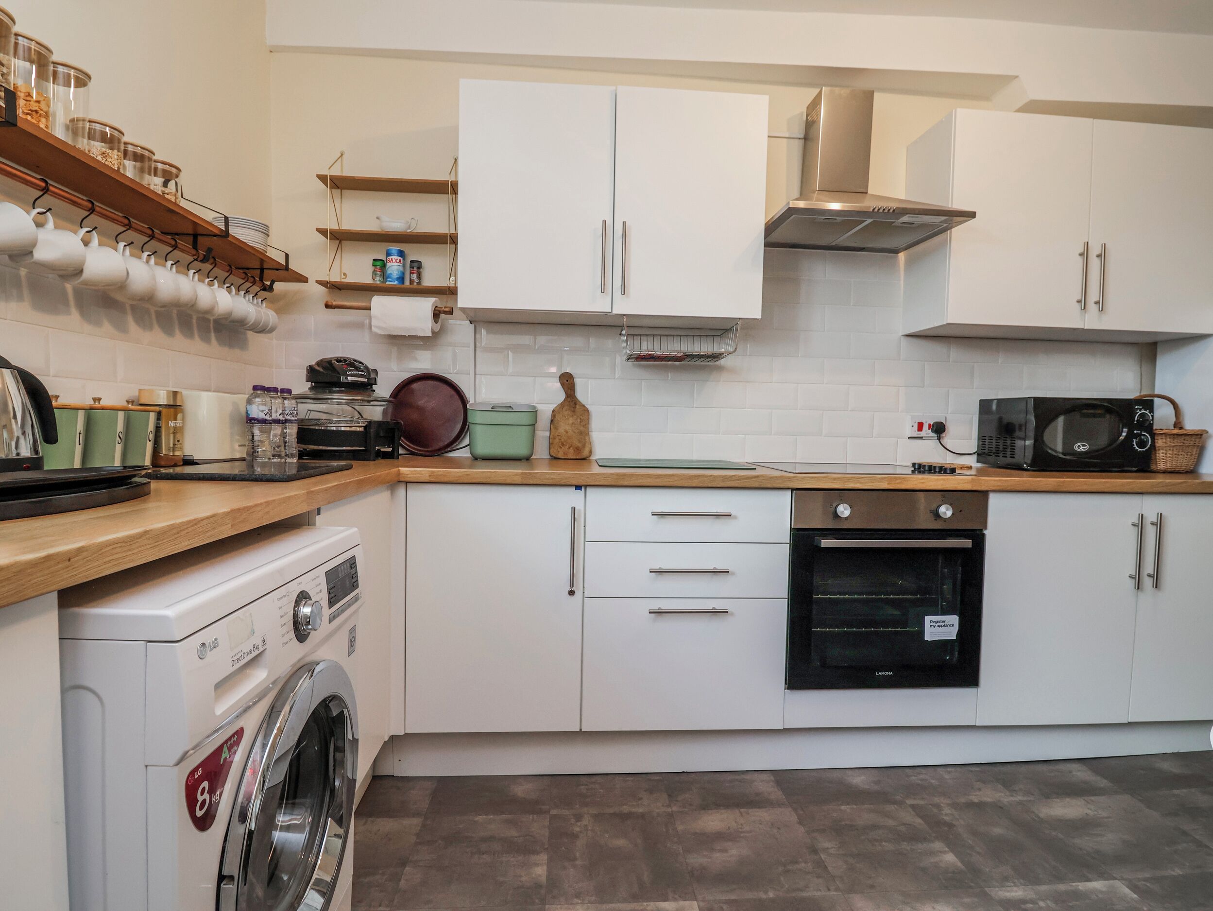 A kitchen with white cabinets, a washing machine, a microwave, and a stove.