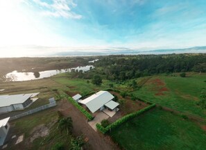 An aerial view of a property with a large building, a smaller structure, and a pond.