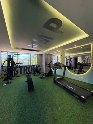 Ein Fitnessstudio mit Trainingsgeräten, Laufband und einem großen Spiegel.