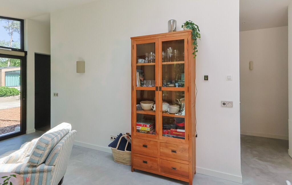 Um quarto com um armário de madeira, uma cesta de vime e uma cadeira listrada.