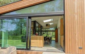 A modern kitchen with a glass door, wooden cabinets, and a dining area with chairs. - De Rode Vos - Enjoying the forest (Lemmer)