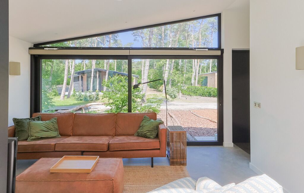 A modern living room with a large sliding glass door leading to a garden.