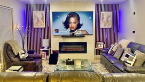 Una sala de estar moderna con sofás de cuero, una mesa de centro de vidrio, un televisor de pantalla plana y paneles decorativos en la pared.