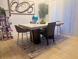 A dining area with a table, chairs, a globe, a plant, and a bookshelf. - Smart 4BR Comfort Suite Massage Chair YQM Airport (Dieppe)