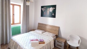 A bedroom with a bed, bedside tables, a chair, a world map artwork, and a window with curtains. - Green Ledro Lake Apartment -A few steps from the Ponale Trail - 800m from the Lake (Molina di Ledro)