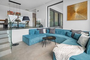 A modern living room with a blue sofa, a black coffee table, and a large window.