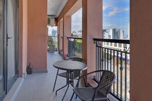 A balcony with a table and chairs, a view of the cityscape, and a building with a blue and white facade. - Stylish Penthouse Heart of the City by Ctha (Cape Town)