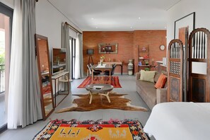 A modern hotel room with a dining area, a sofa, a large mirror, and a decorative rug. - Stylish Penthouse Heart of the City by Ctha (Cape Town)