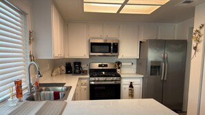 A modern kitchen with white cabinetry, stainless steel appliances, a built-in microwave, a gas stove, and a refrigerator.