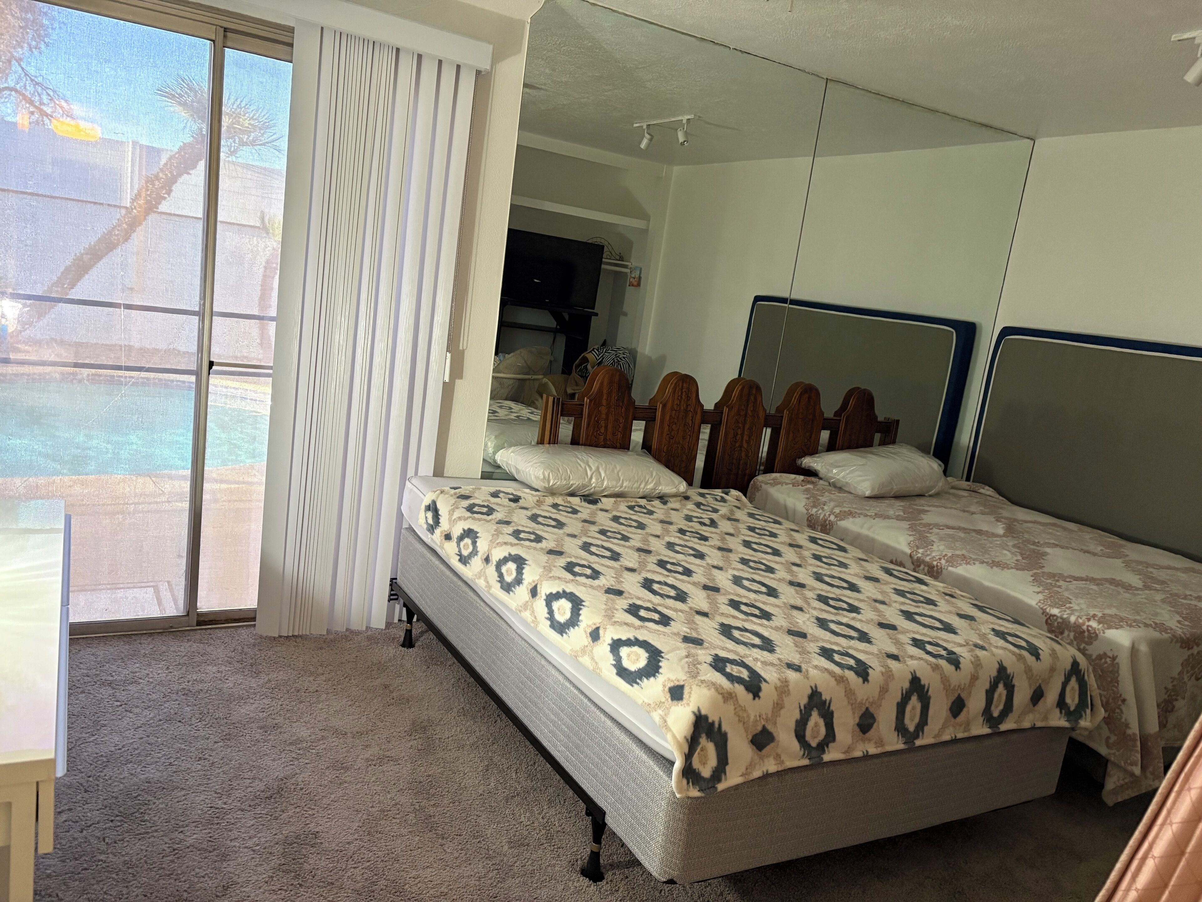 Un dormitorio con una cama grande, un espejo y una puerta corrediza de vidrio a un balcón.
