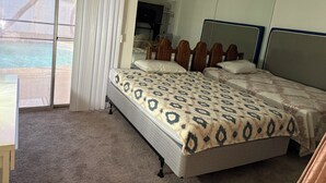 A bedroom with a large bed, a mirror, and a sliding glass door to a balcony.