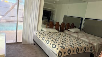 Un dormitorio con una cama grande, un espejo y una puerta corrediza de vidrio a un balcón.